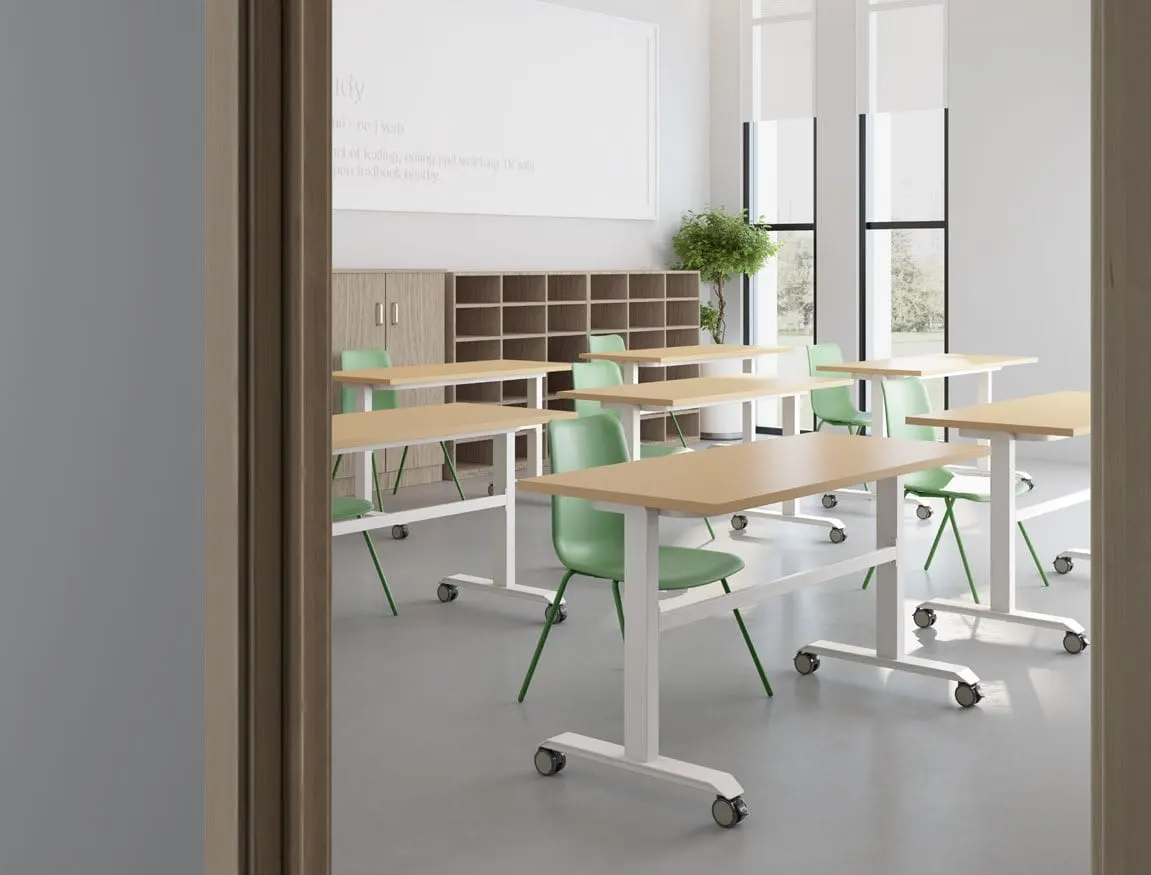 Classroom of mobile oak-top tables with white frames and casters and green shell chairs, with whiteboards behind