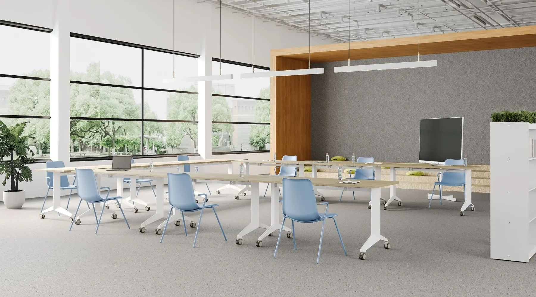 Rows of white-based flip-top training tables with light-blue shell chairs in a spacious room with large windows