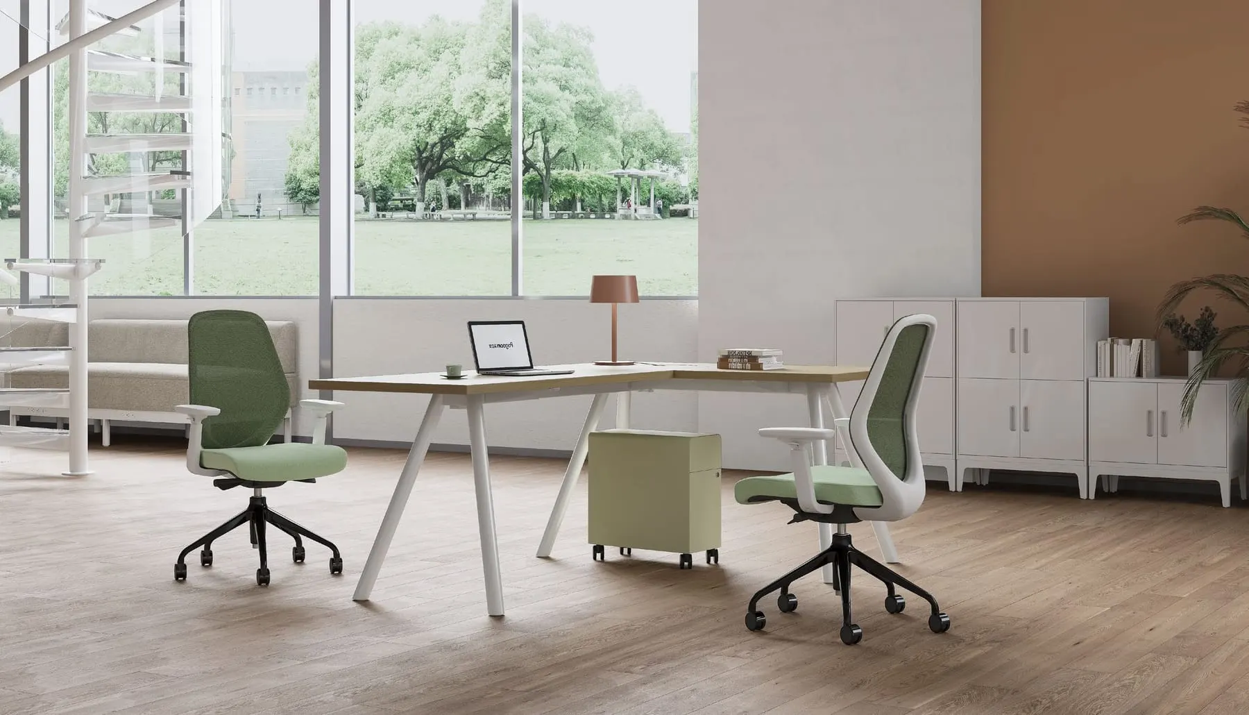 Two green-mesh ergonomic task chairs, one black frame and one white, at an L-shaped desk with sage pedestal